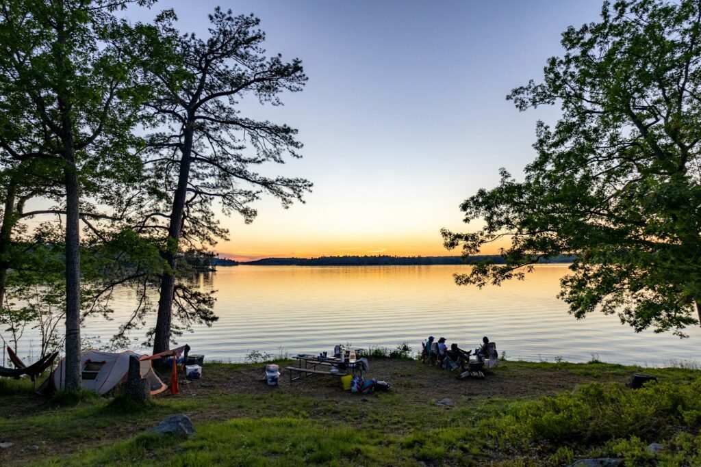 Friends camping by a lake at sunset